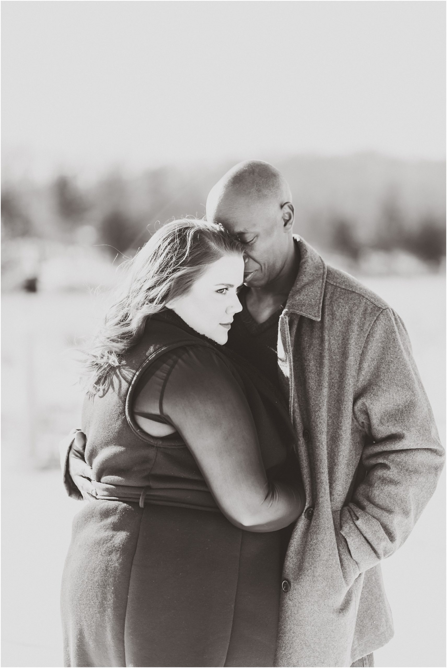 black and white image of mixed race couple hugging in the snow