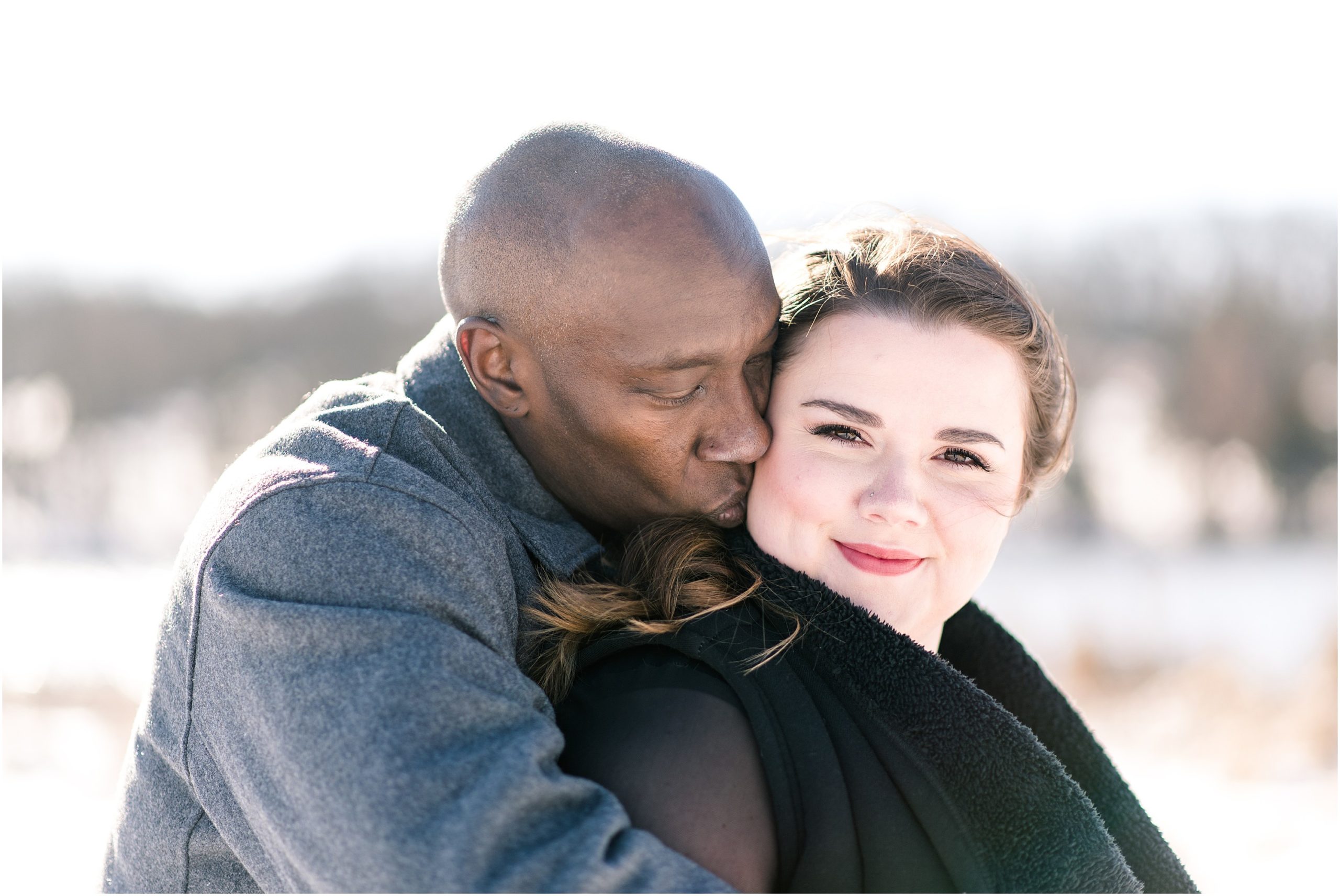 mixed race engaged couple kissing in the snow for engagement session