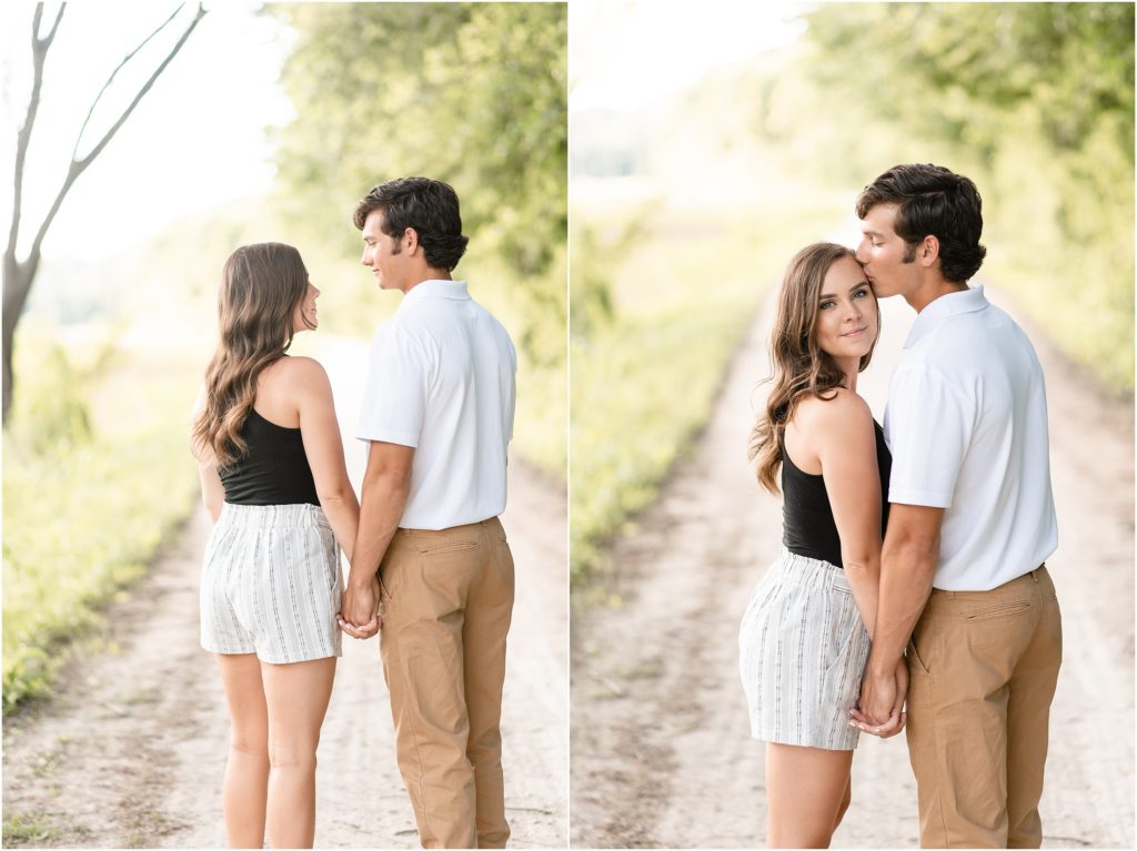 engaged couple posing and kissing on gravel path in sunlight
