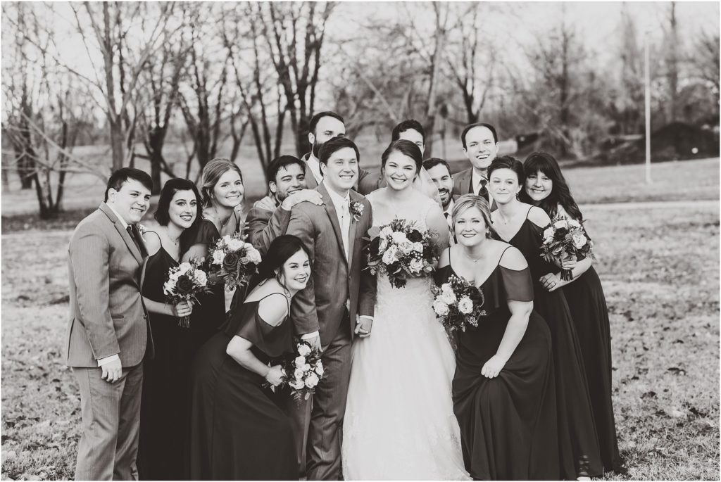 black and white photo of wedding party surrounding bride and groom