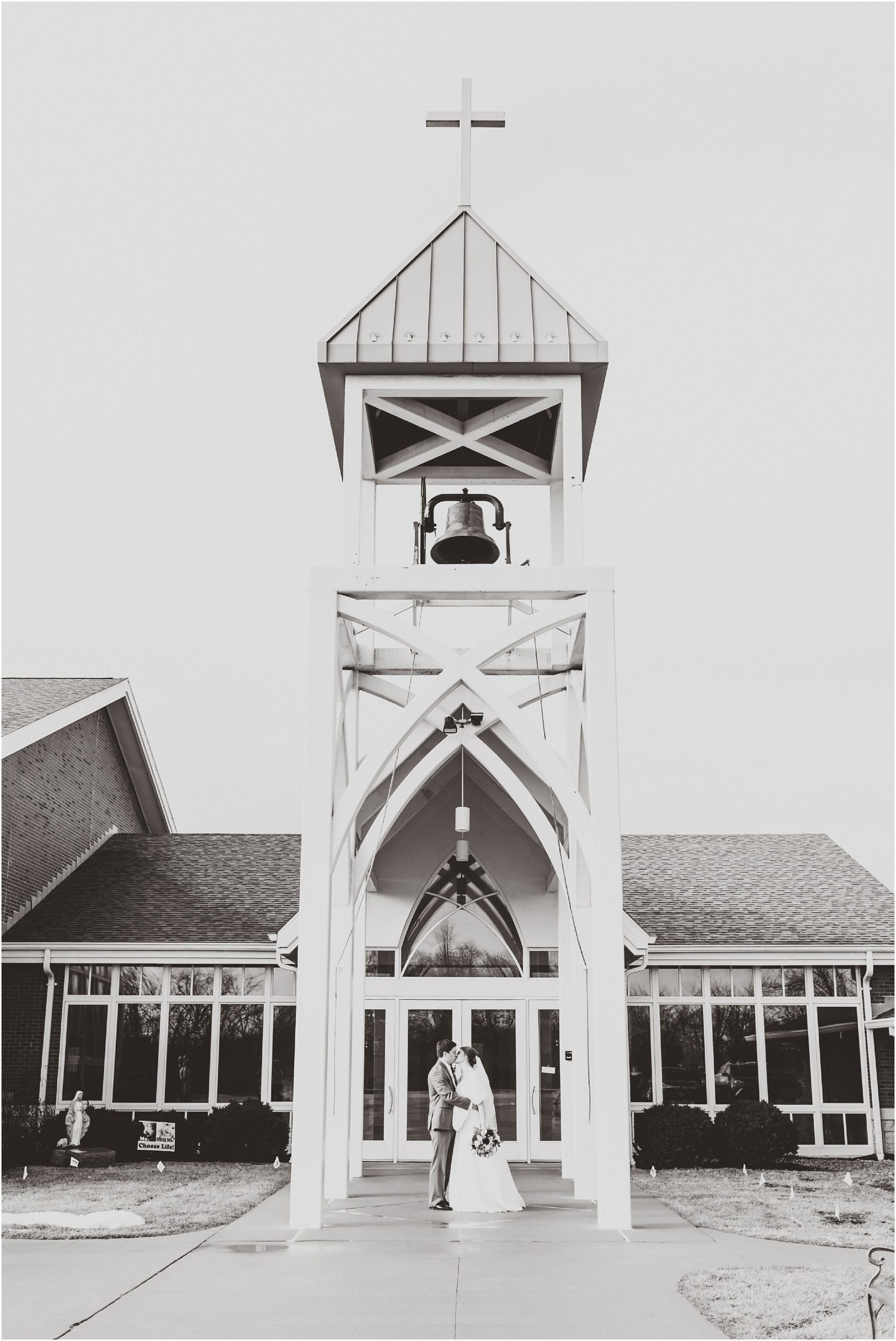 bride and groom portrait outside st. andrews church bell tower in black and white
