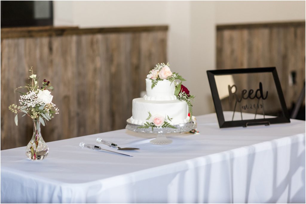 capital bluffs event center wedding cake with white and wine colored roses on cake table