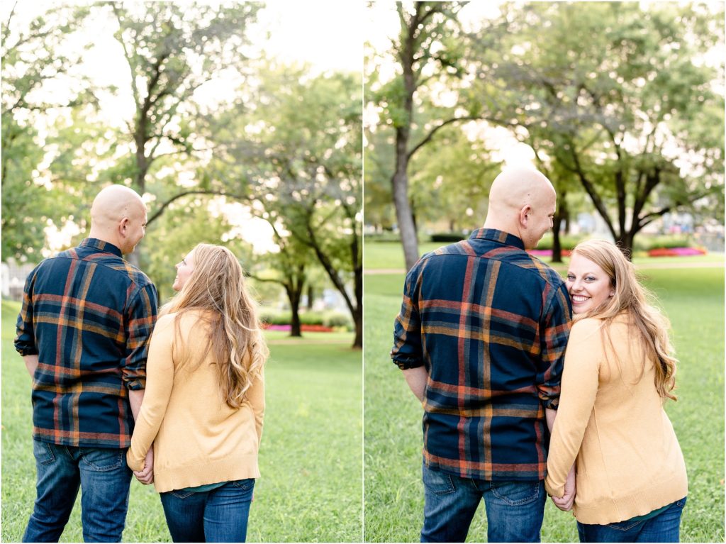 couple wearing fall colored clothes standing in grass under trees for engagement photos in Jefferson City, MO