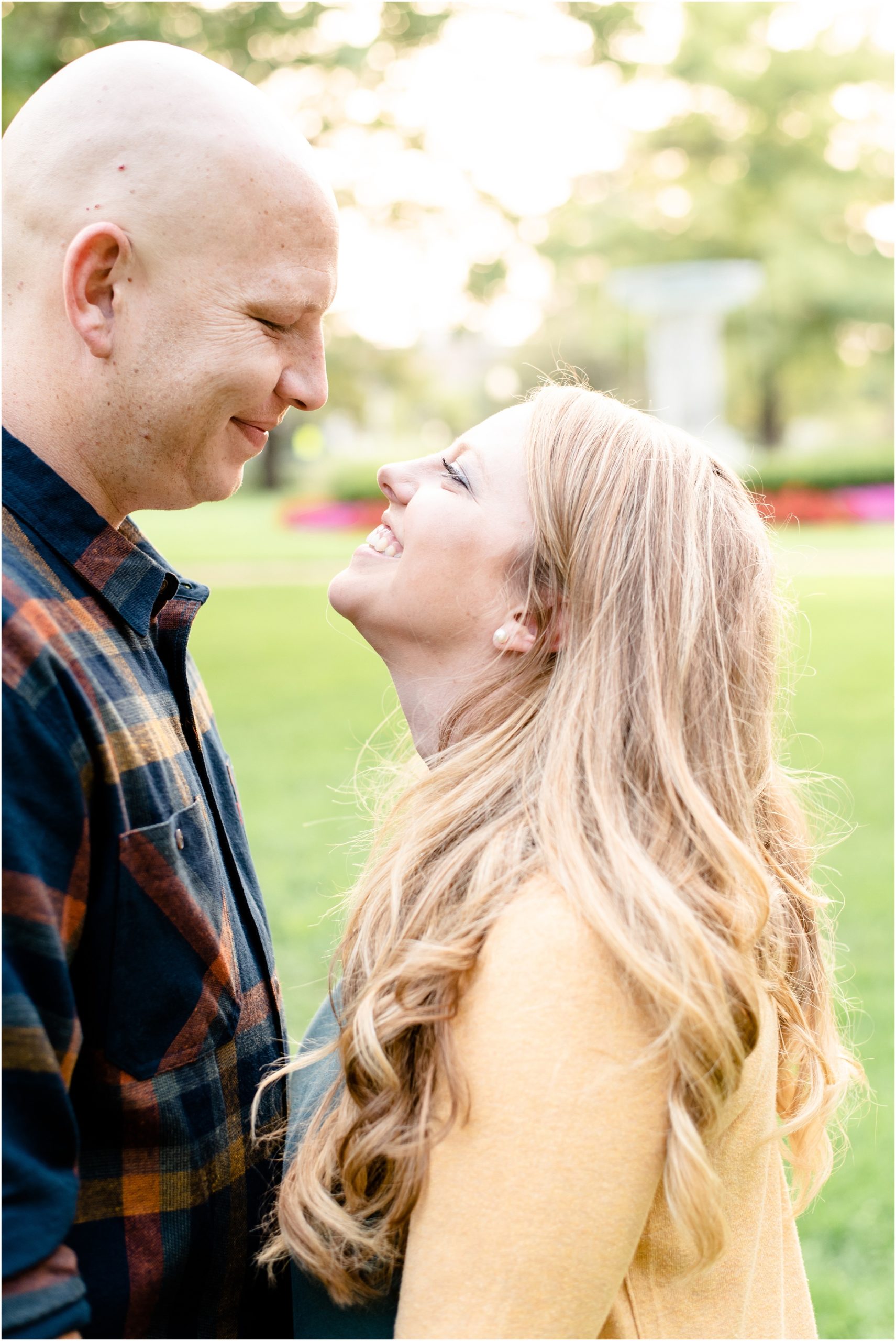 engaged couple smiling at each other in front of Missouri capitol fountains and flowers for engagement photos