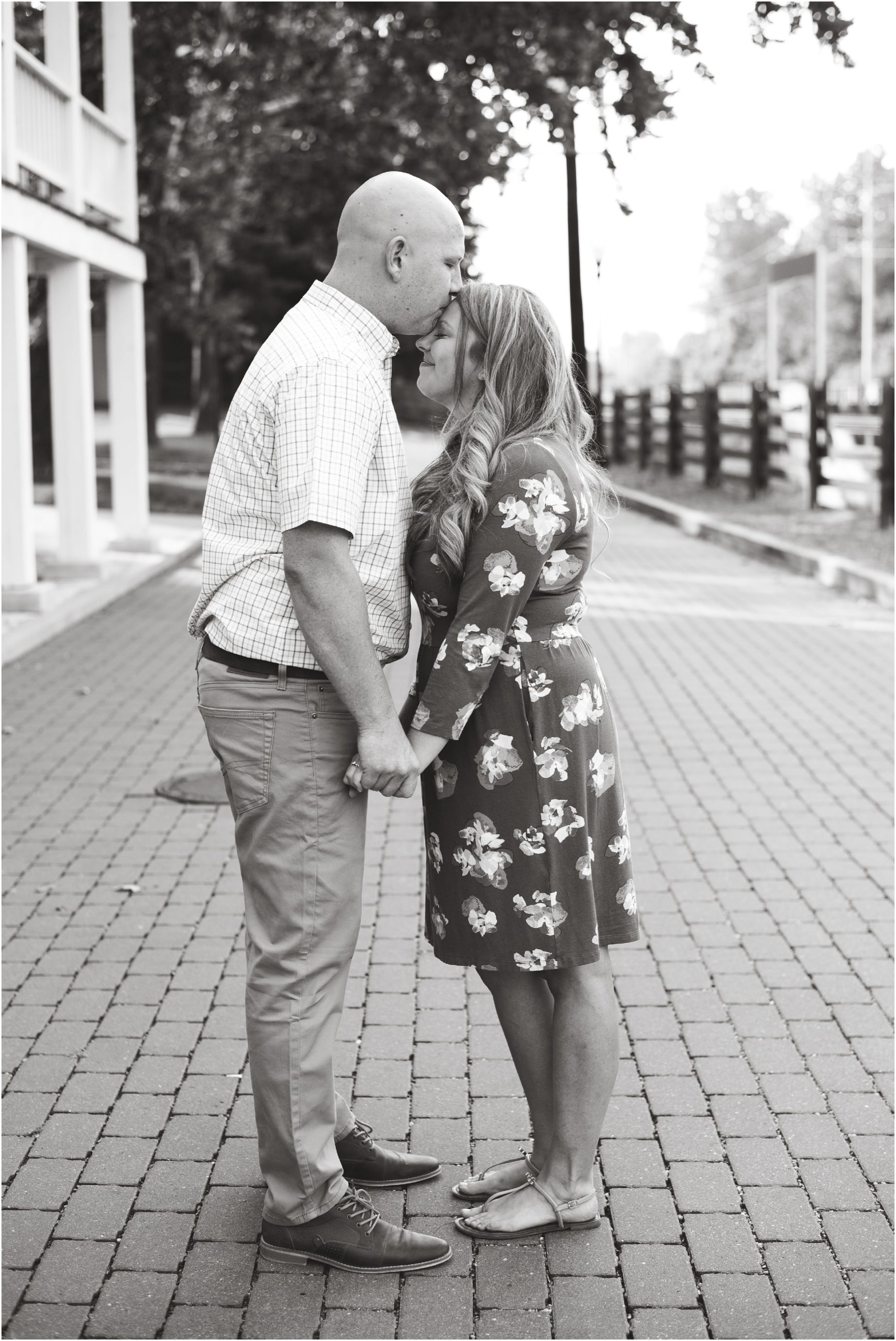black and white image of man kissing fiancé on forehead for engagement photos