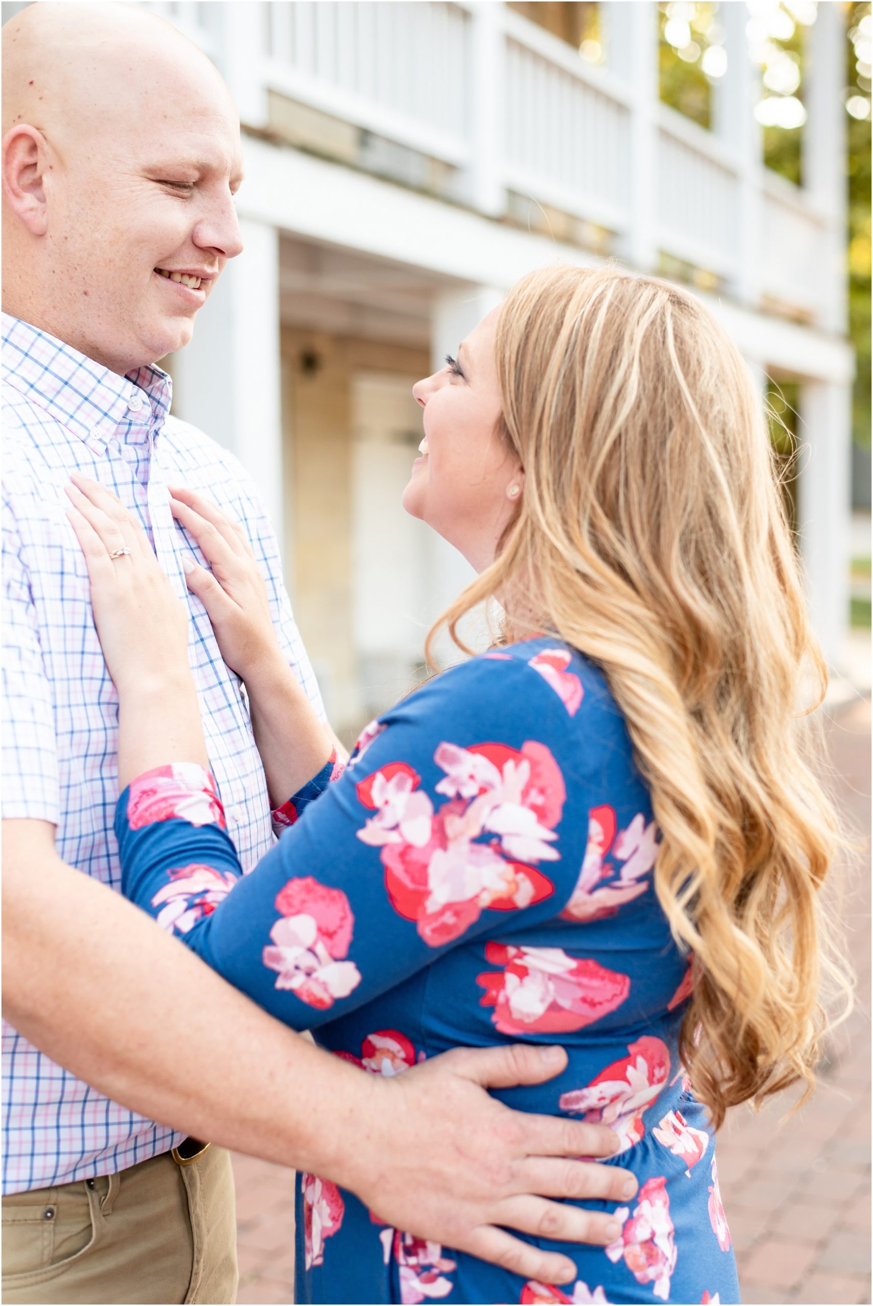 engaged couple posing together with girls hands on his chest and wearing blue floral dress