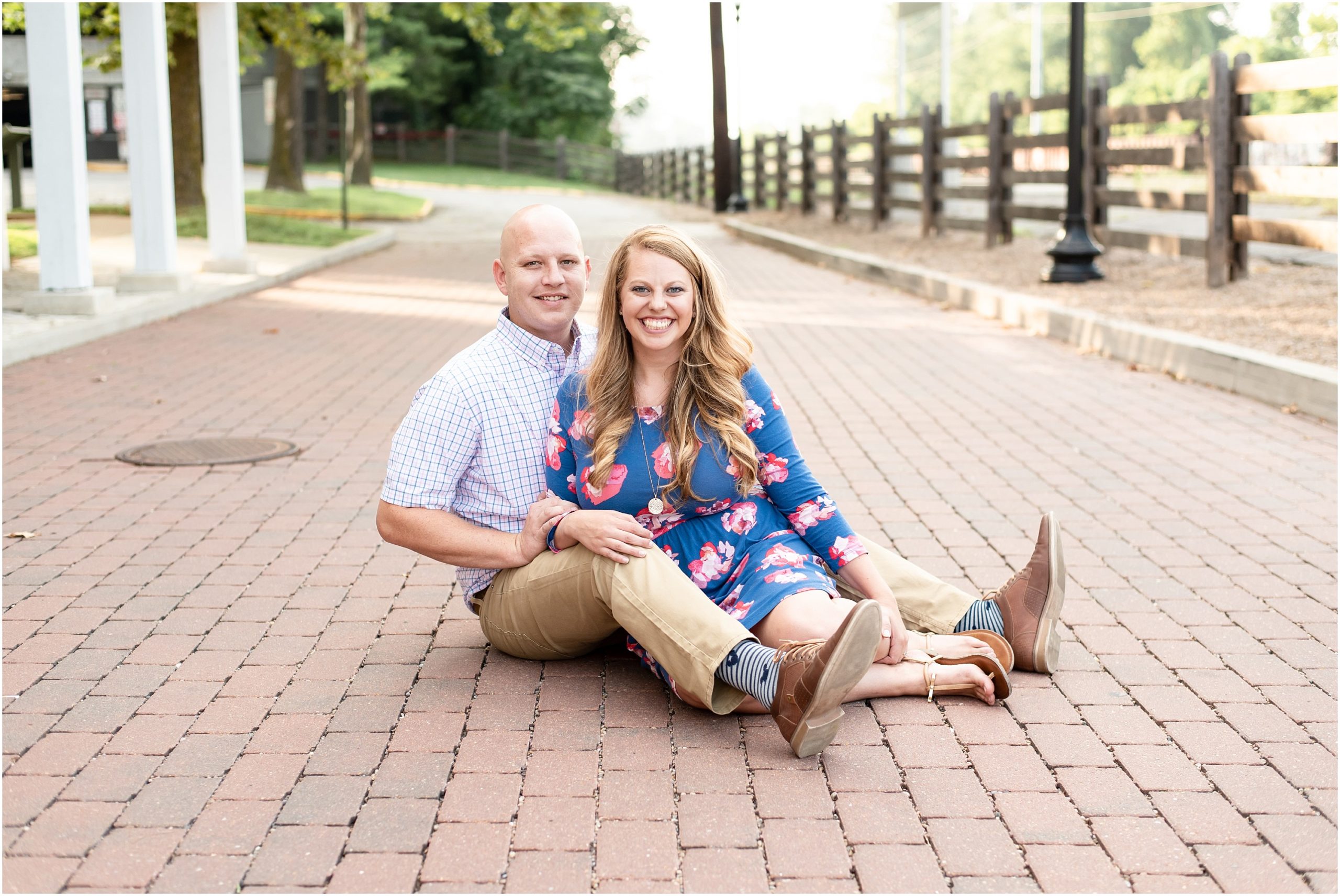 engaged couple sitting on brick road for engagement session in downtown Jefferson City, mo
