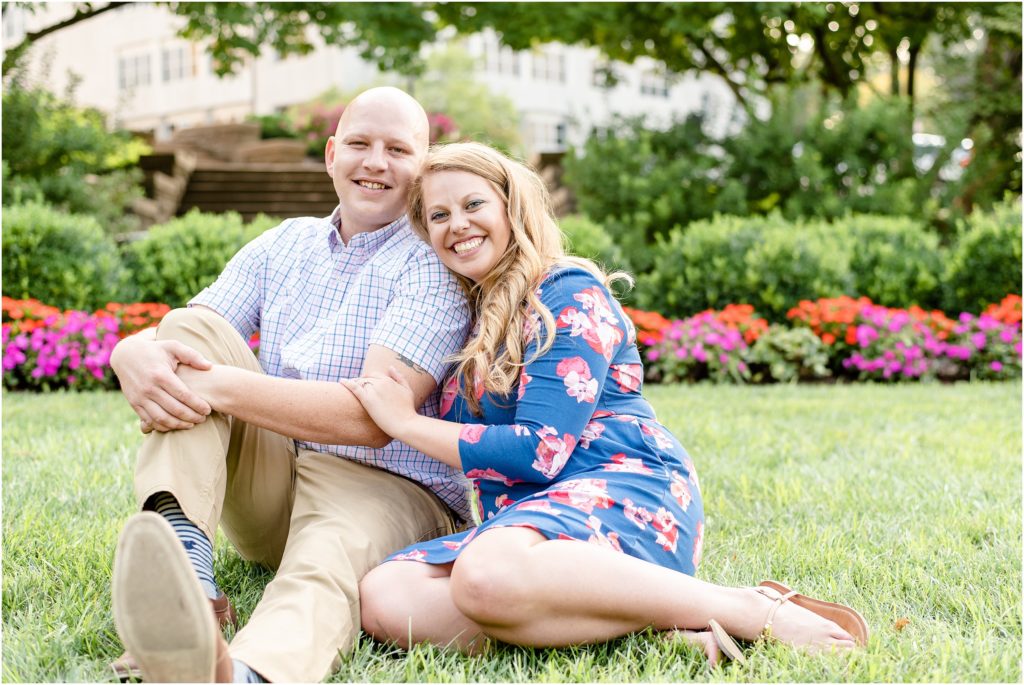 couple sitting together on grass with flowers in the background at governor's garden engagement session