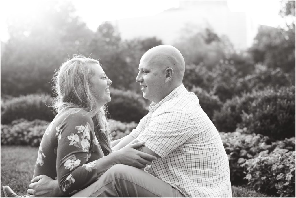 black and white image of couple sitting facing each other on grass for Jefferson City engagement photos
