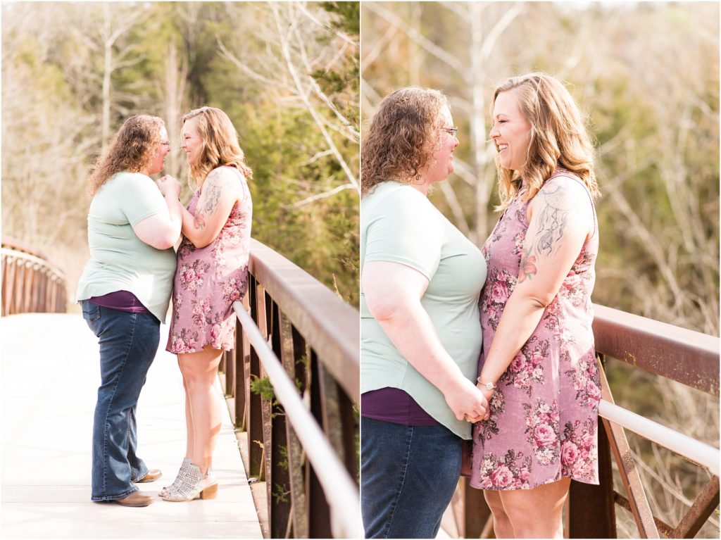 lesbian couple laughing together on bridge at Jefferson City greenway trail for engagement session