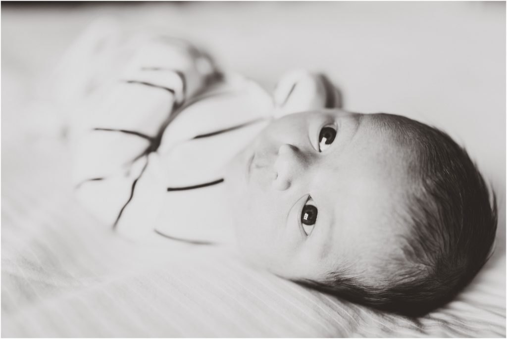 black and white image of newborn baby boy looking up at camera