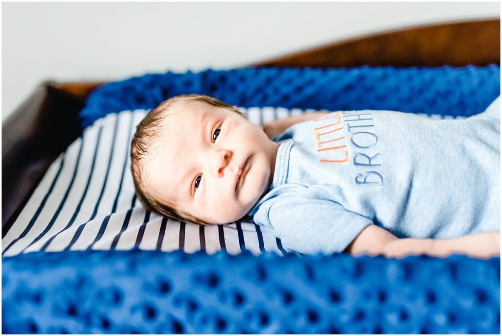 baby boy looking at camera on blue changing table