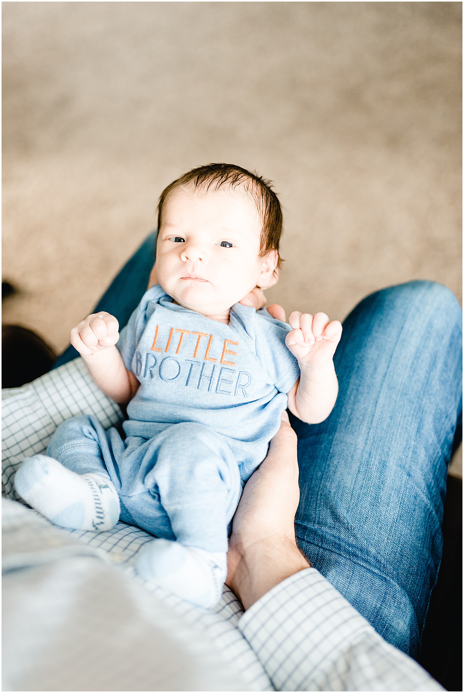 image of baby boy looking up at camera laying on dad's lap for columbia,  mo newborn session