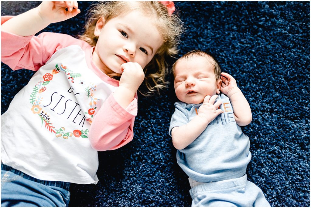 big sister and baby brother laying on rug for columbia, mo newborn session
