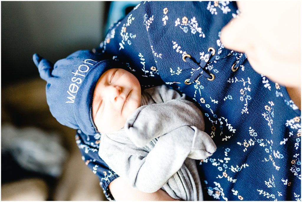 mom holding baby boy with name on blue hat