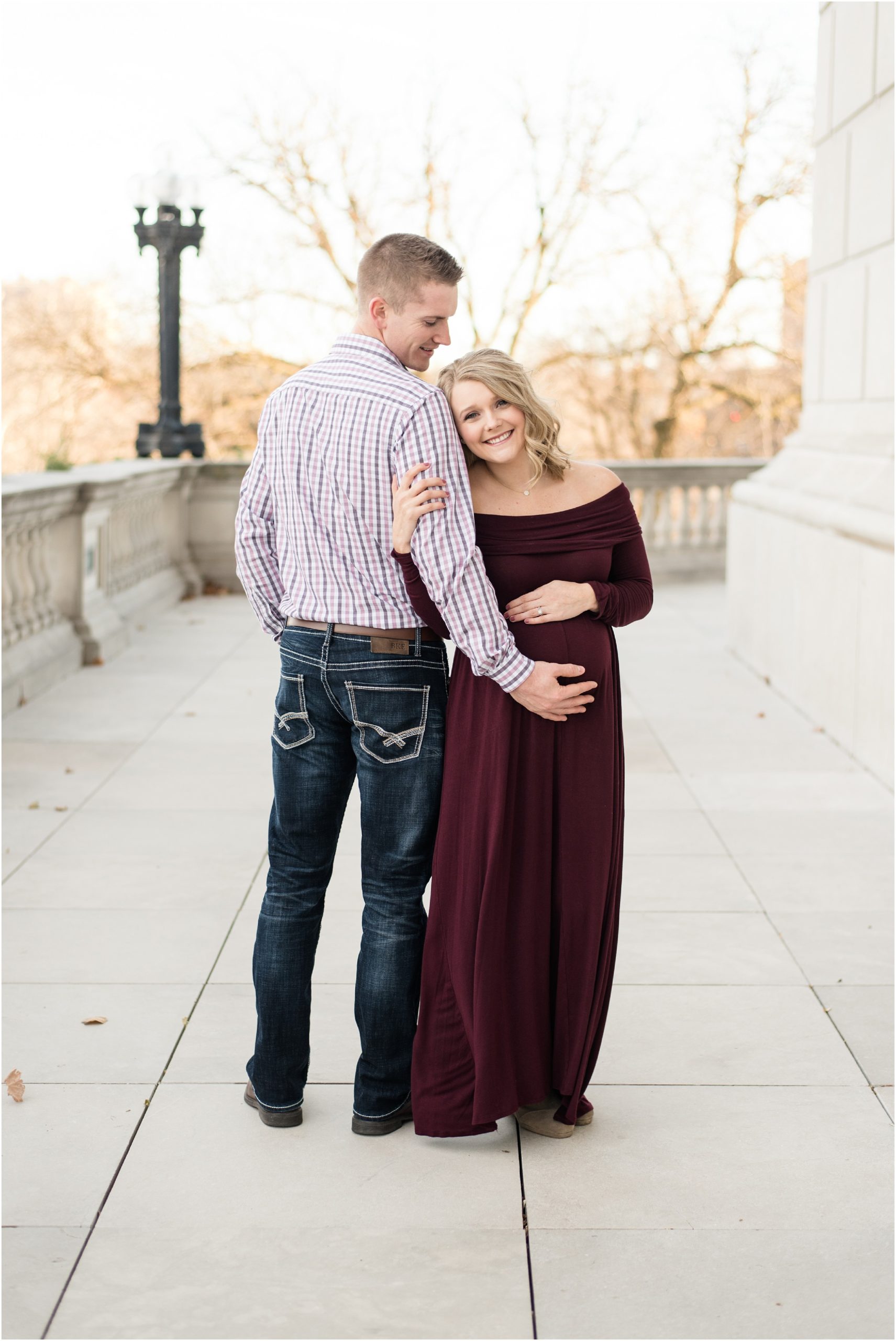 couple posing holding belly at missouri state capitol building for maternity session