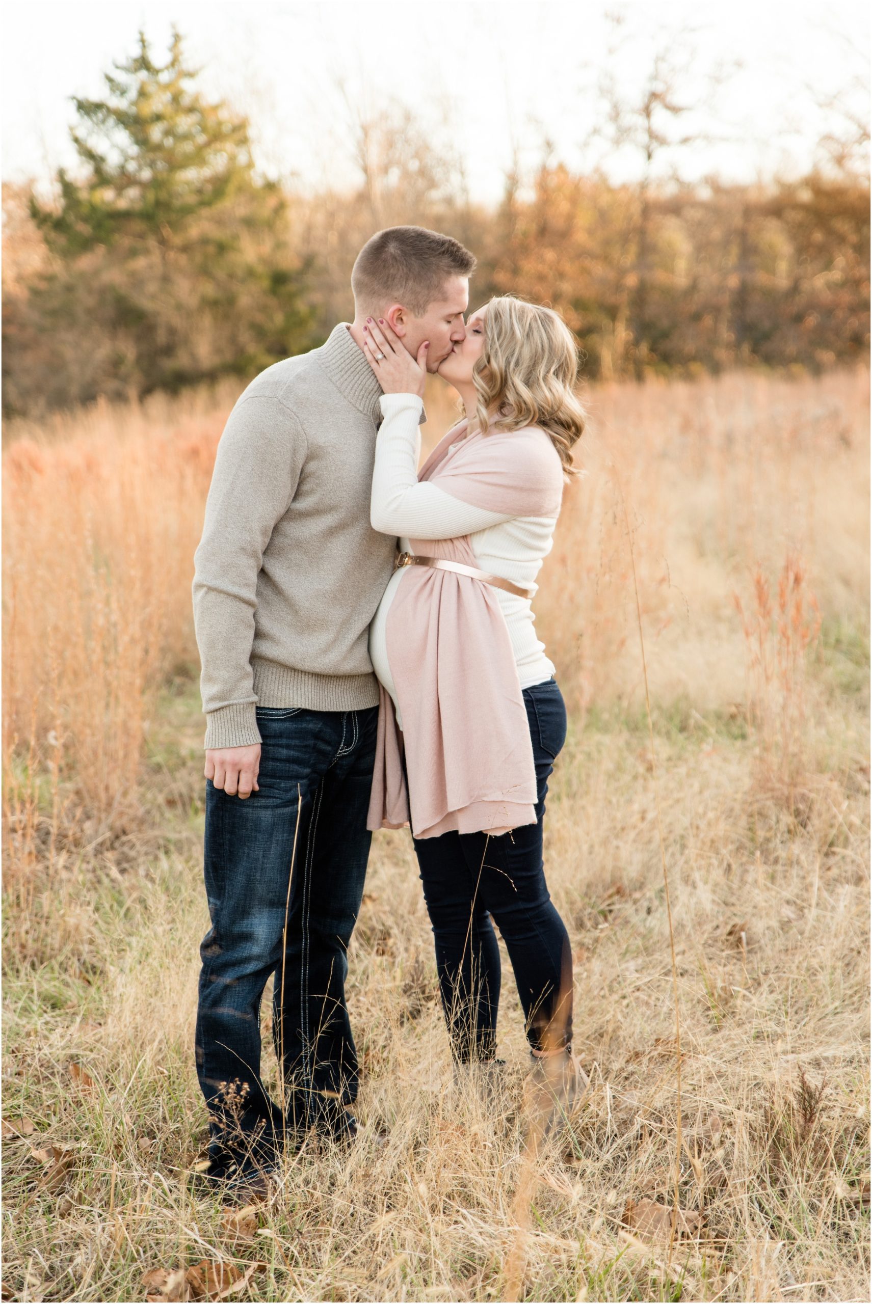 couple kissing in grass field for binder park maternity session