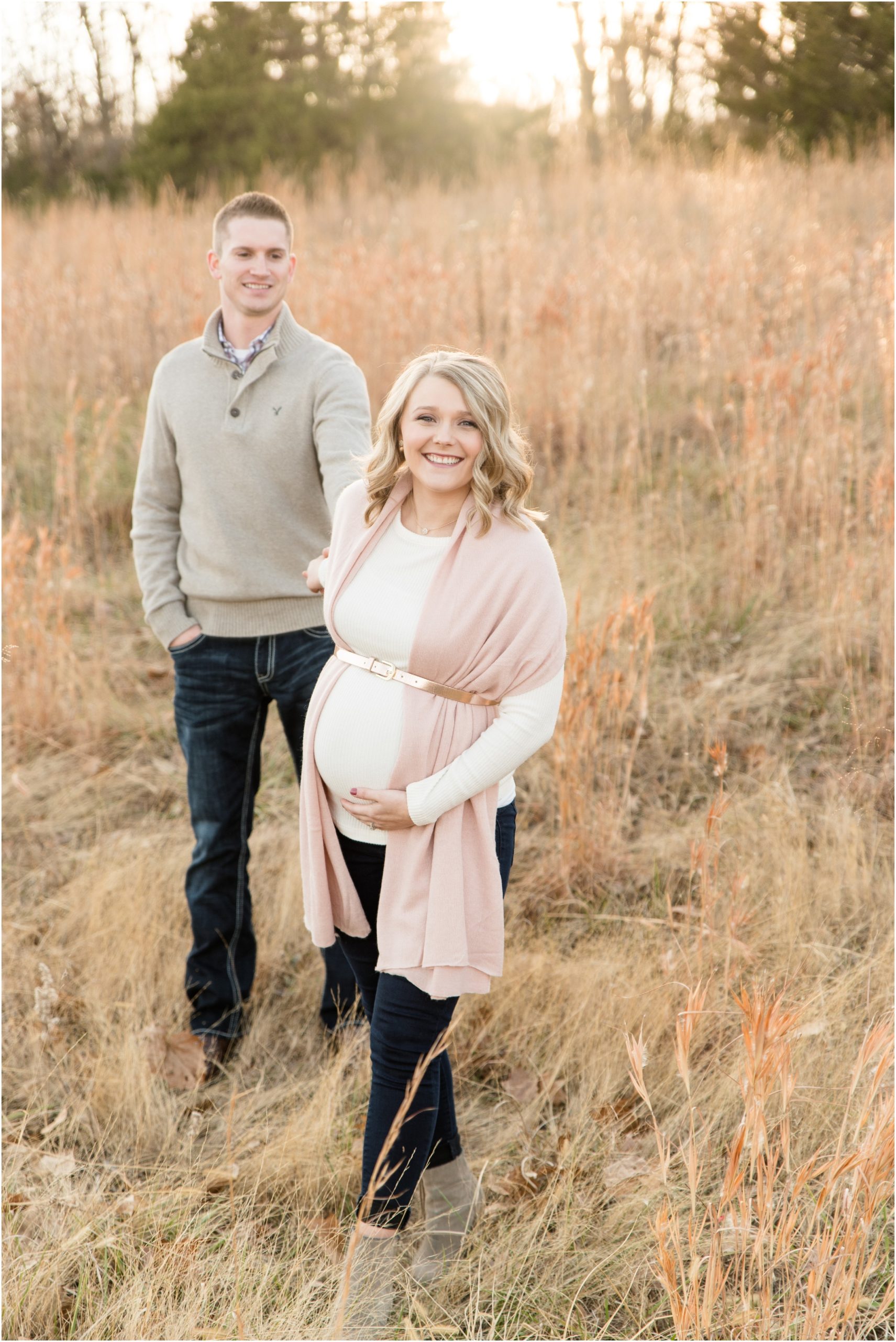 couple walking and holding baby belly in field of grass at binder park for maternity session