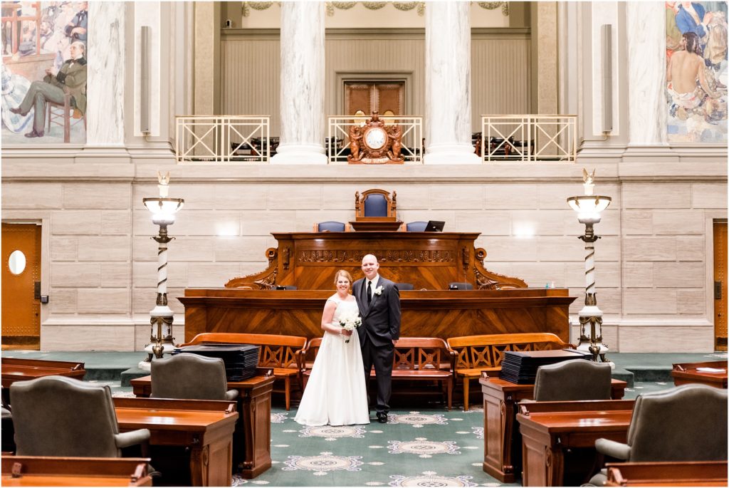 bride and groom posing on the senate chamber floor of the missouri state capitol building