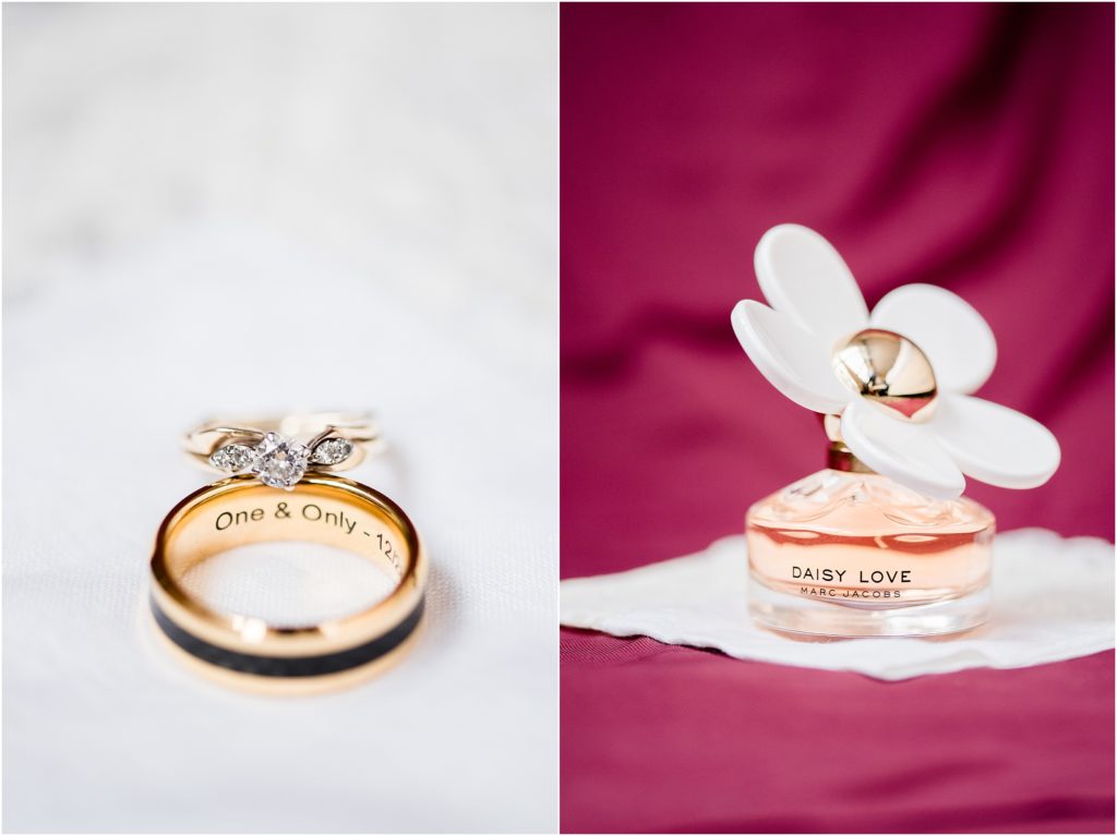 wedding details of rings and daisy love marc jacobs perfume on maroon background