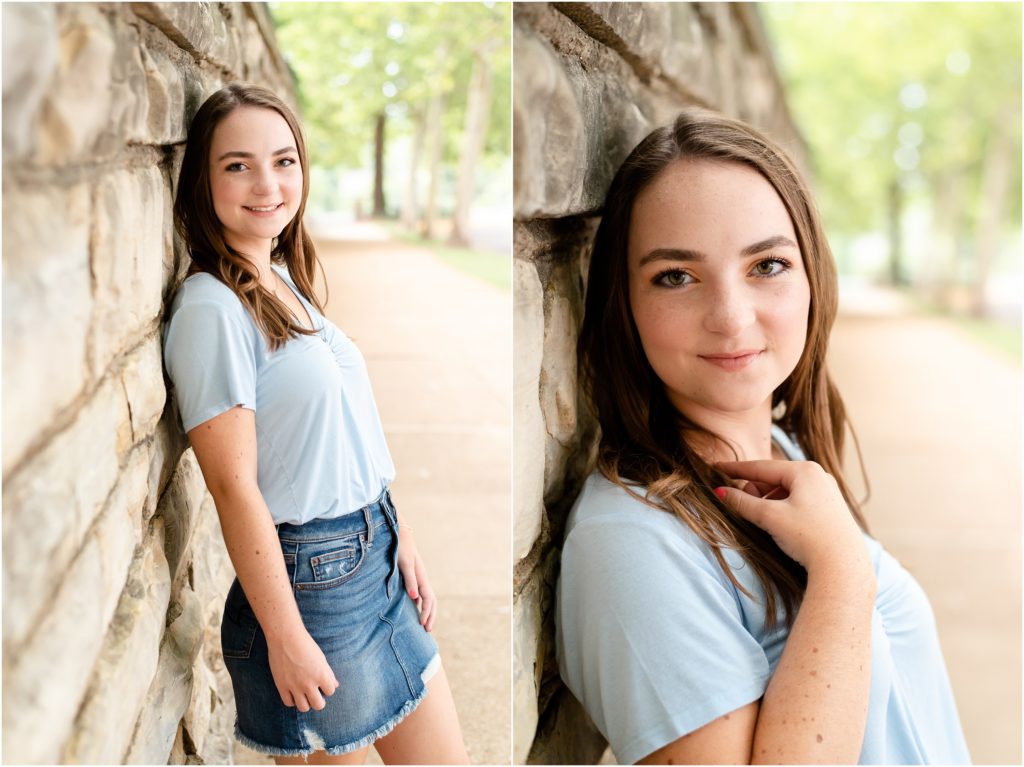 senior girl leaning against large rock wall on sidewalk by missouri governor's mansion for senior photoshoot