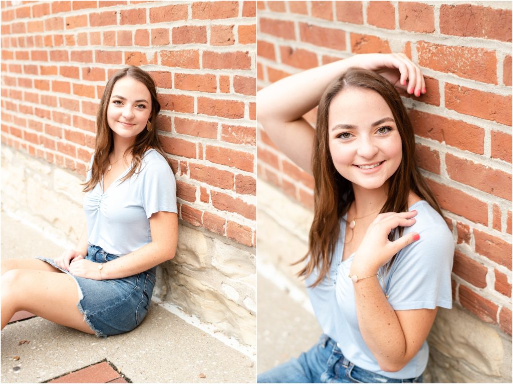 senior girl in blue shirt and jean mini skirt leaning against brick wall for senior photos