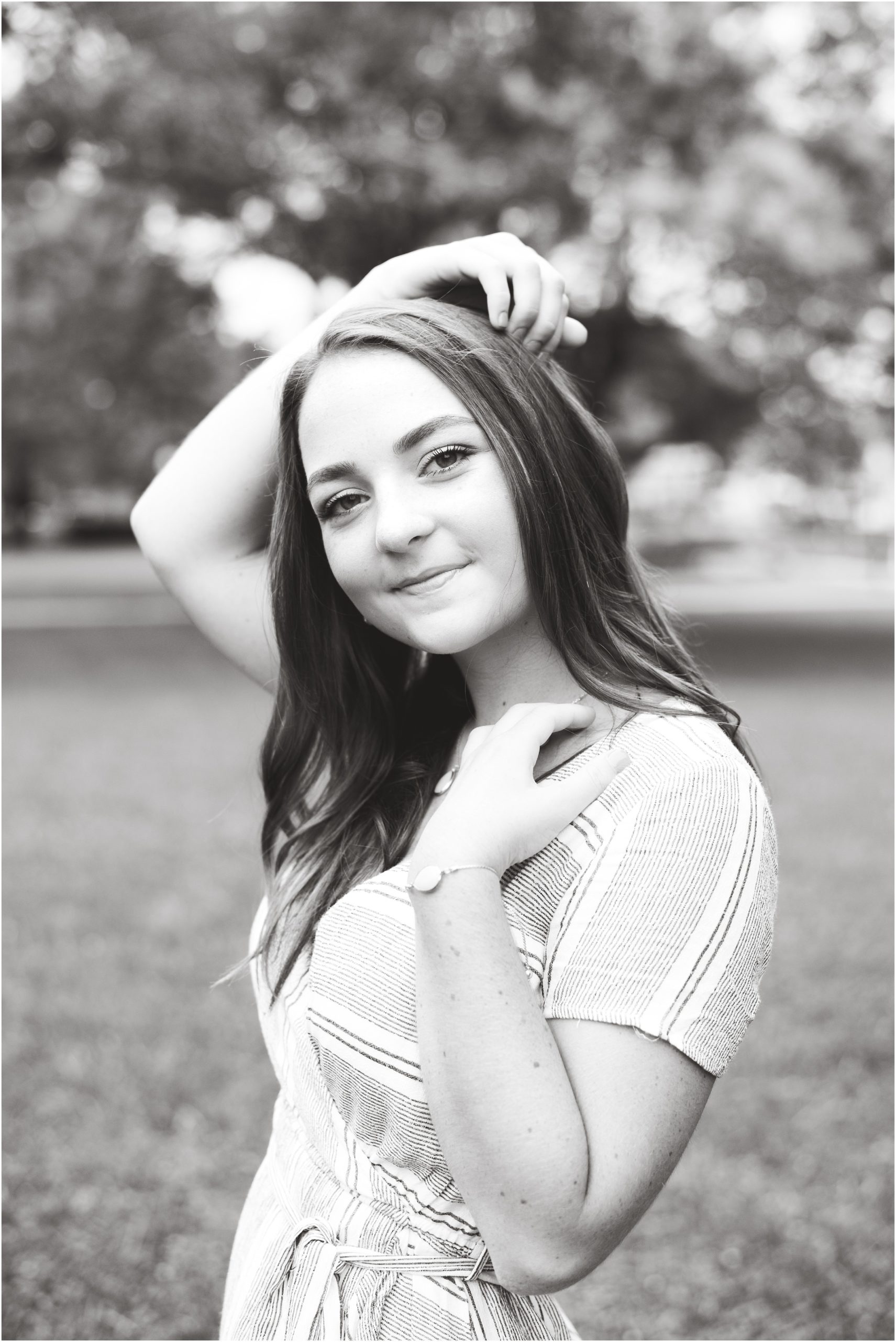 black and white image of senior girl posing with arm over head for senior pictures