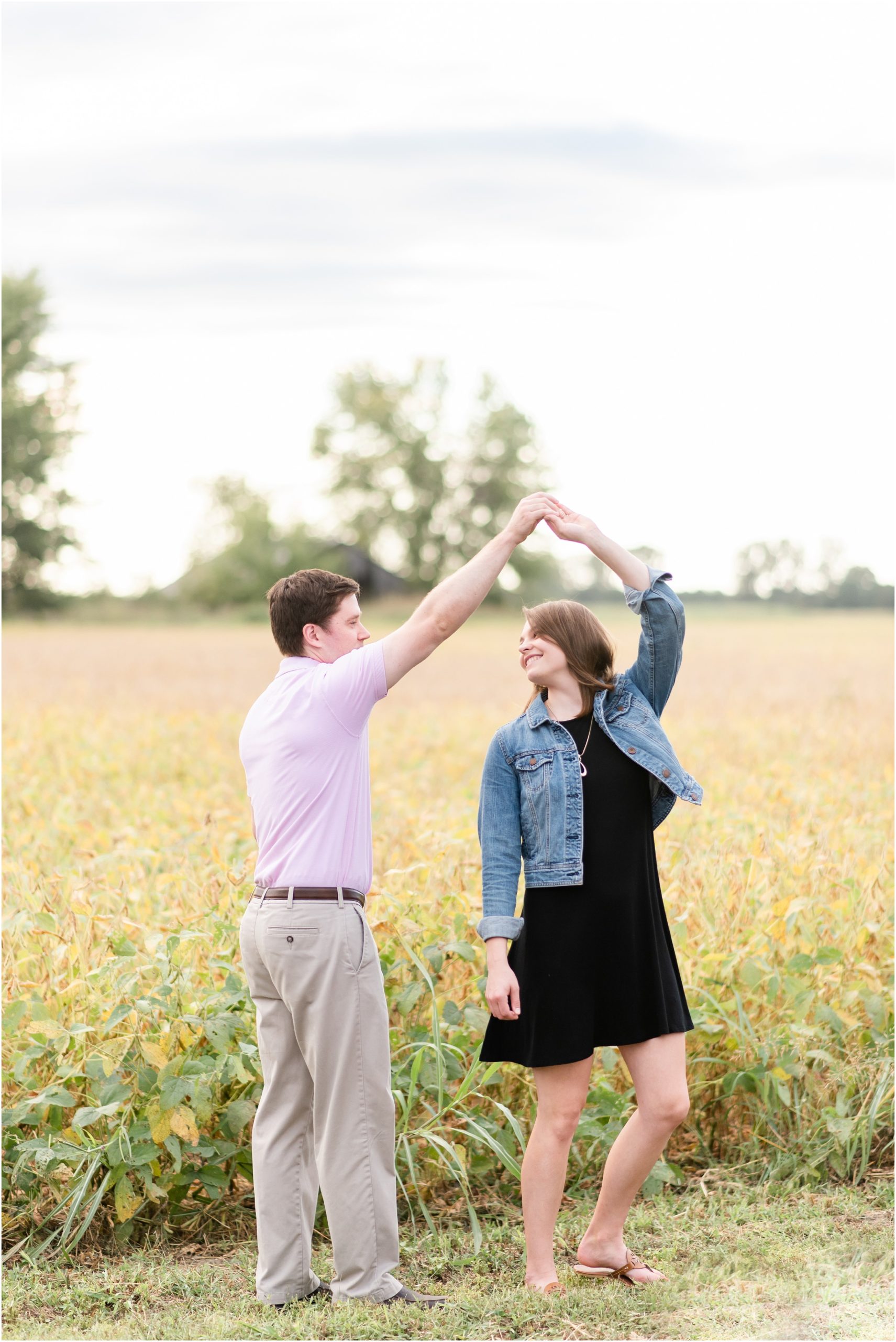 engaged couple dancing and spinning in field for engagement session