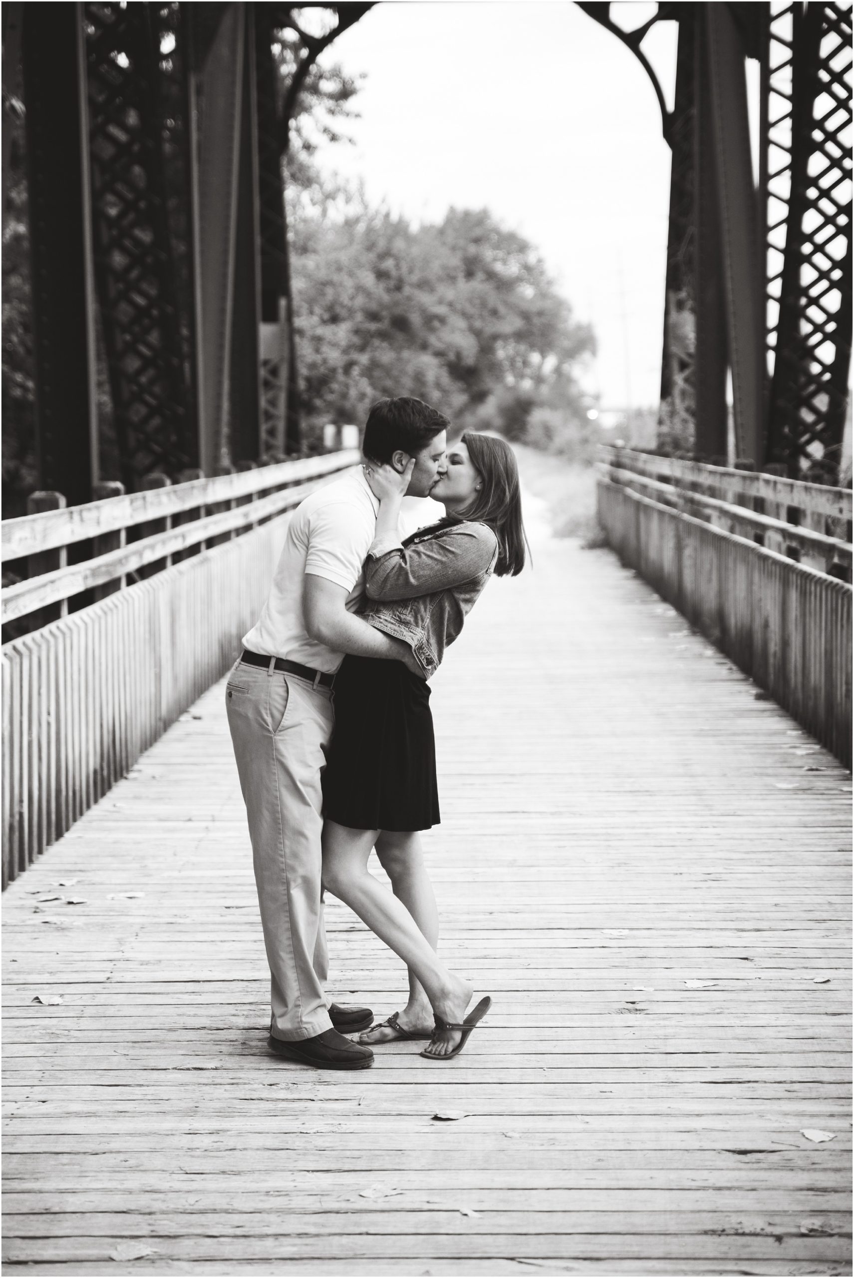 black and white image of engaged couple kissing in the middle of Katy trail bridge for Jefferson City, mo engagement session