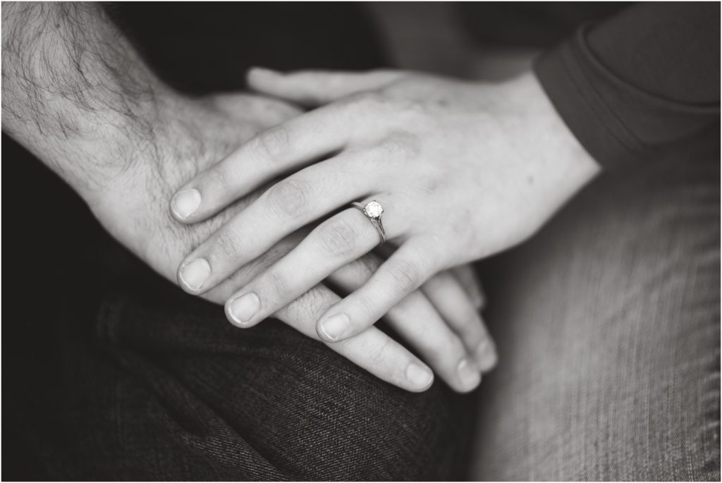 black and white image of engaged couples hands together with engagement ring details
