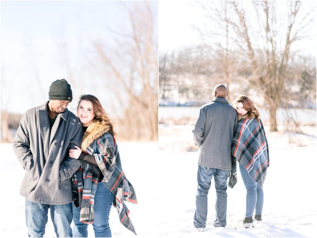 couple posing in the snow for snowy engagement session wearing a plaid cape