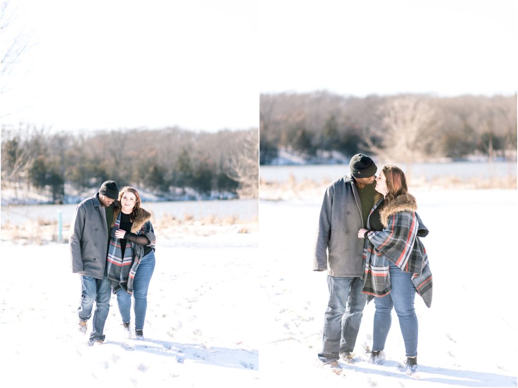 engaged couple walking in snow toward camera and kissing