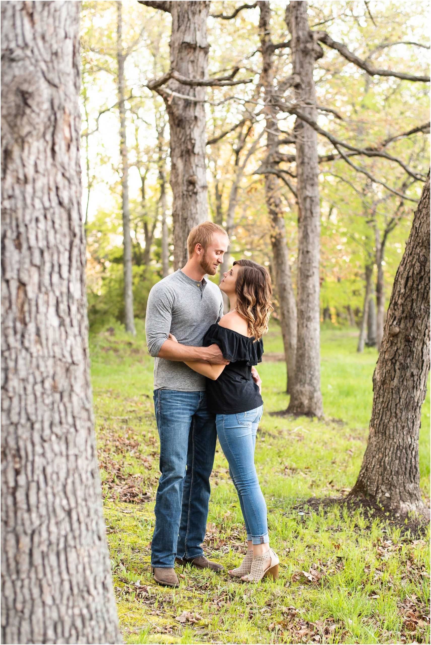 couple wearing jeans hugging each other under trees for linn, mo couples portraits