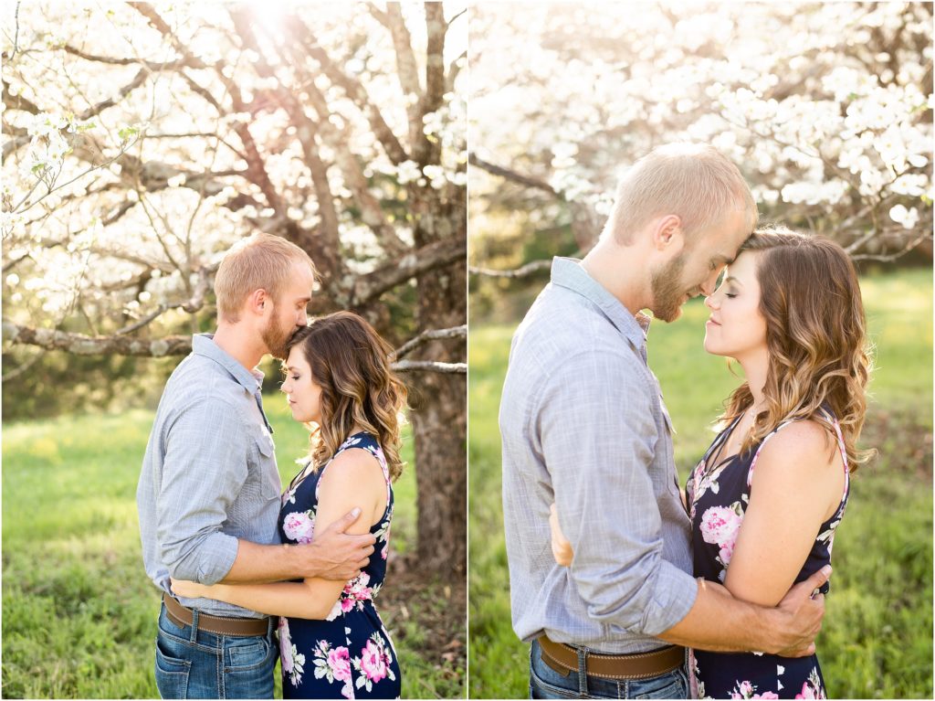 couple kissing and touching foreheads under large white tree for portraits 