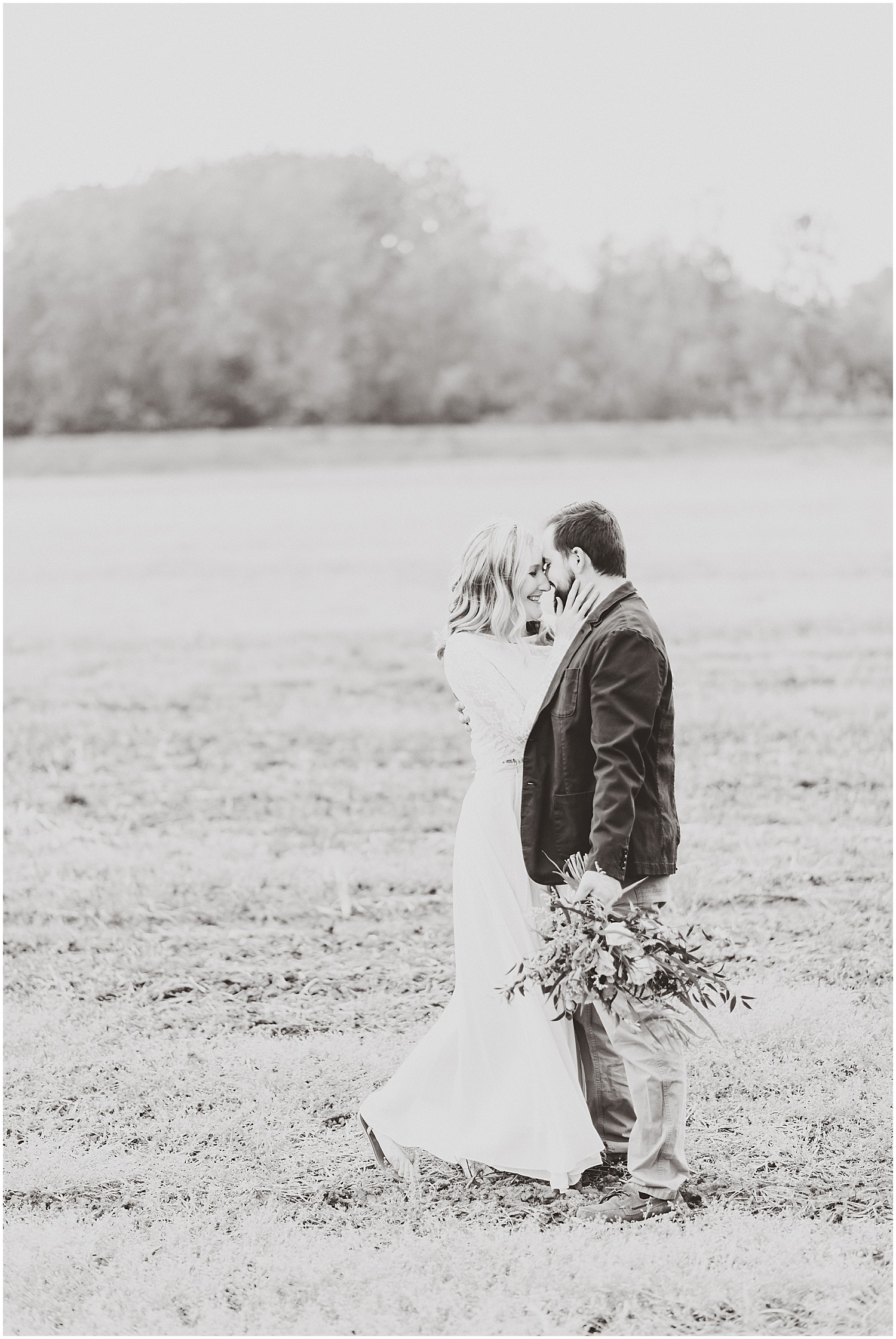 black and white image of couple kissing in a field