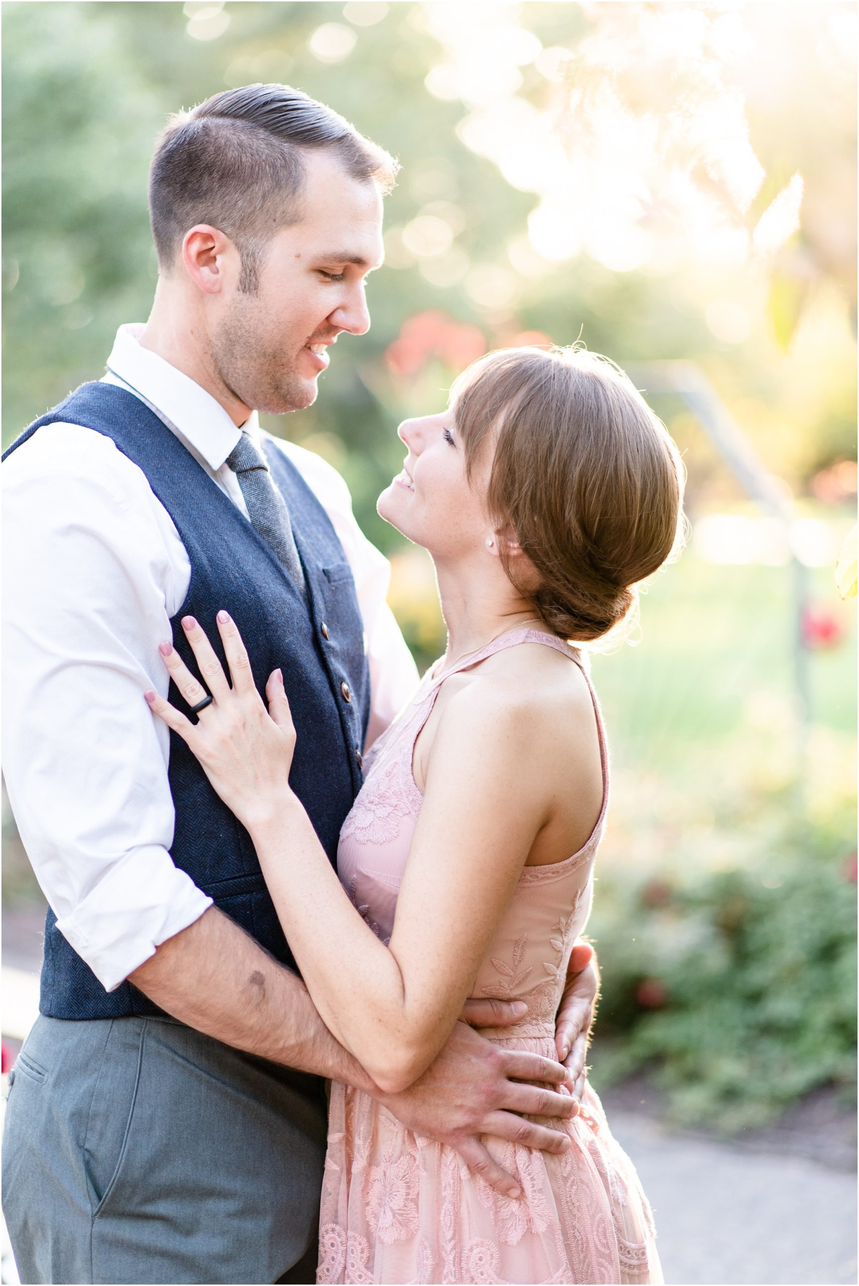 couple kissing in the sunlight glow at shelter gardens in columbia, mo during engagement session