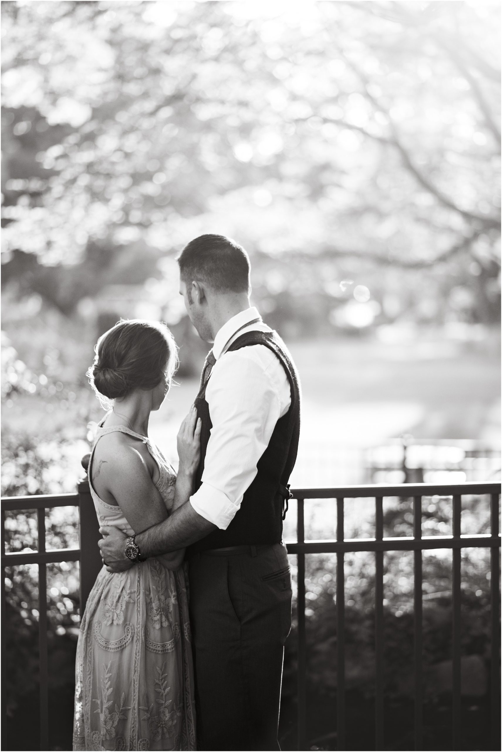black and white image of couple standing by a fence looking away from the camera at shelter gardens