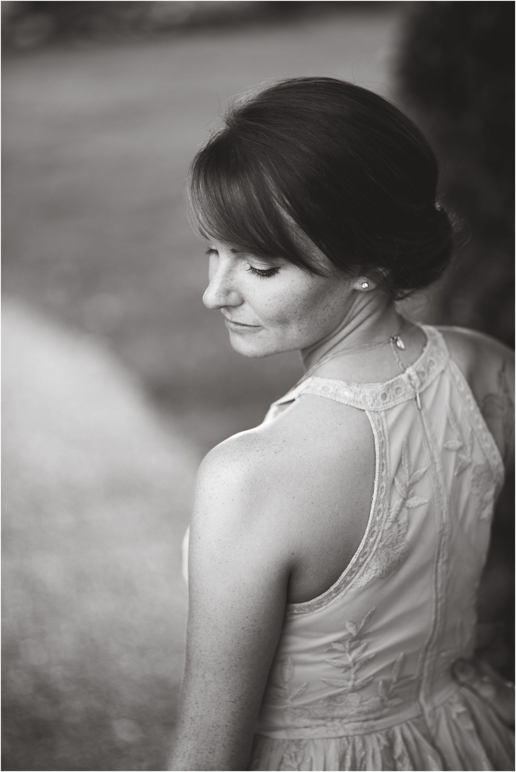 black and white image of girl looking down over her shoulder during engagement session