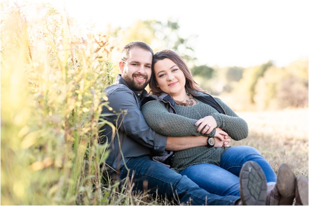 couple sitting and hugging by tall grasses during runge nature center engagement session