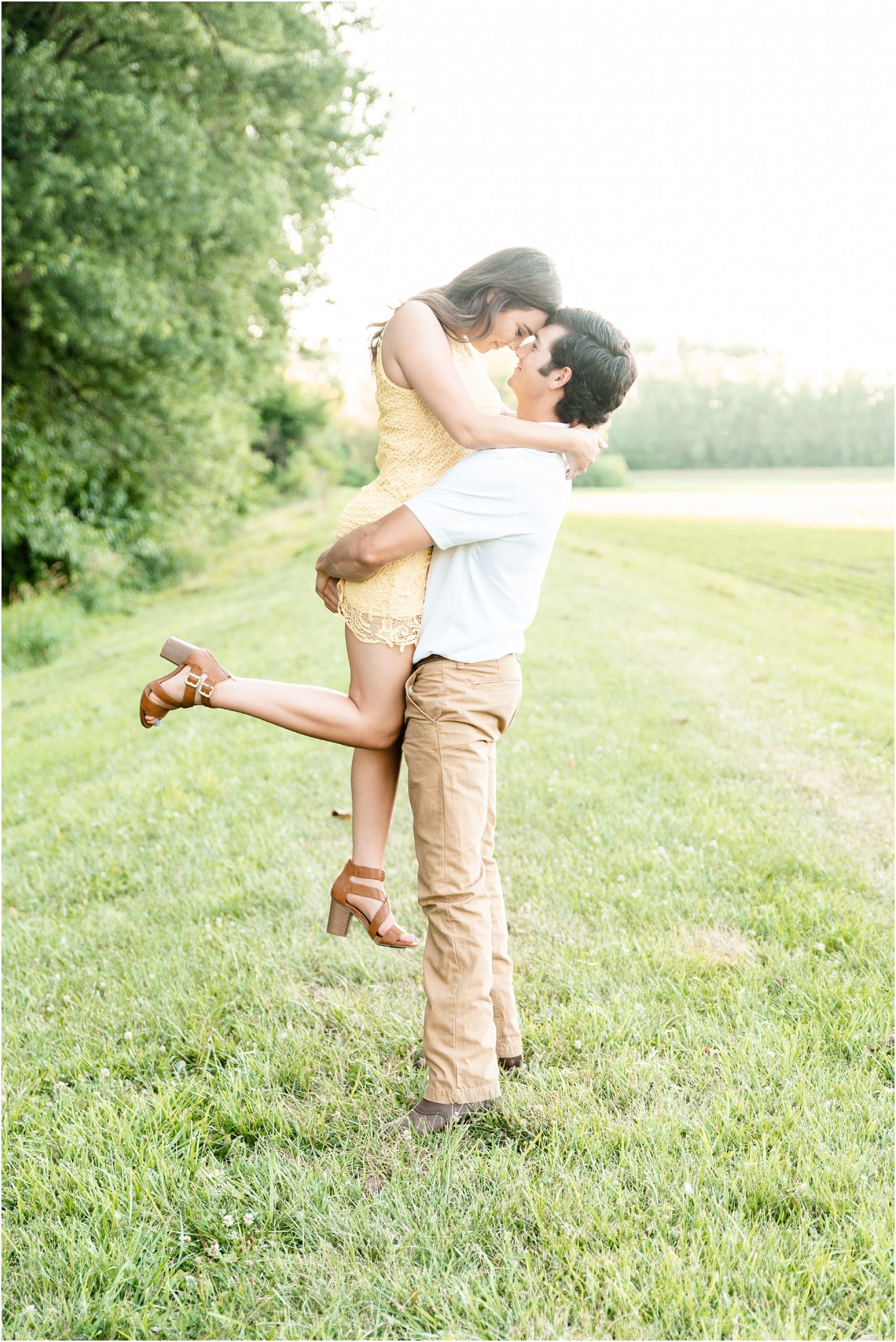 boy lifting up fiancé for engagement photos foreheads touching
