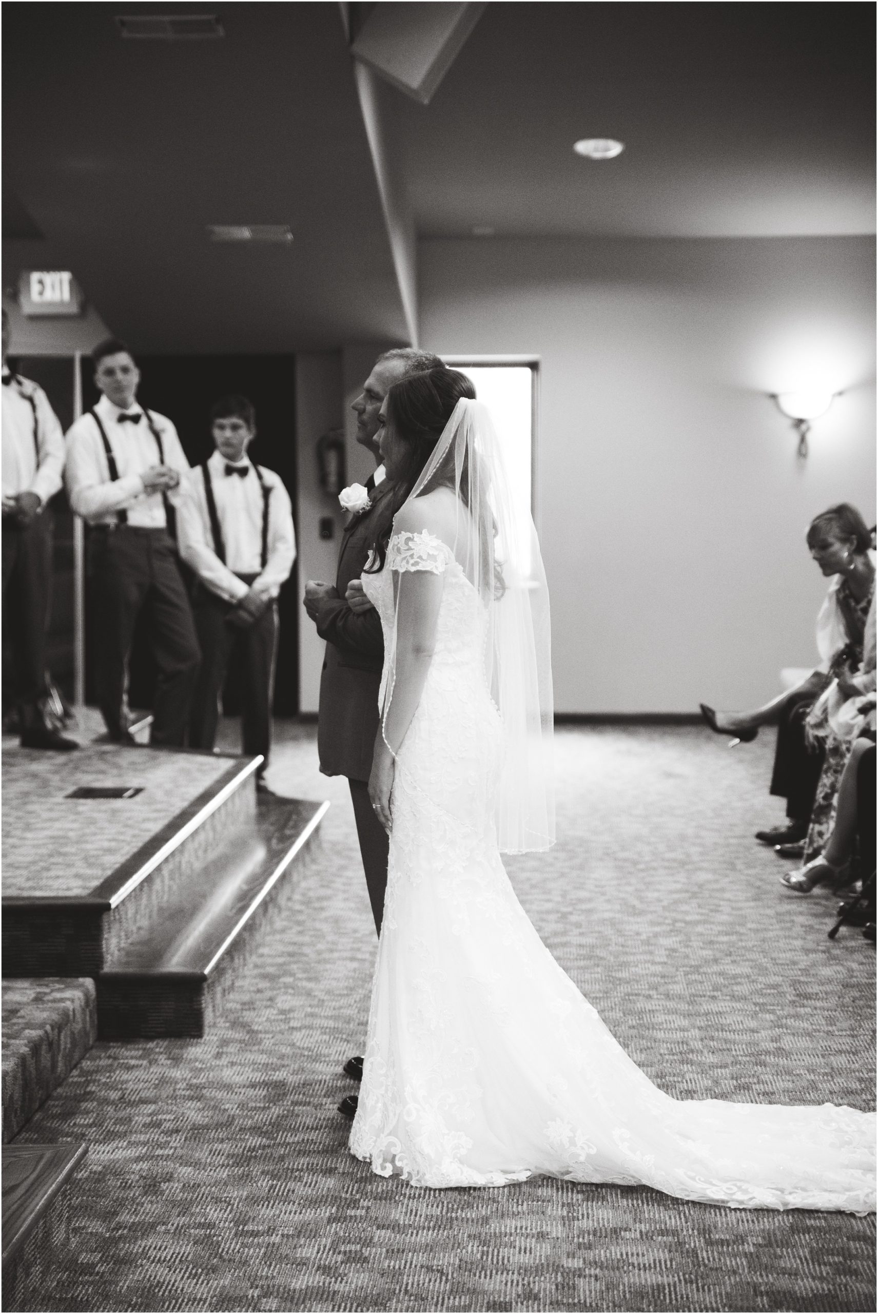 black and white image of bride standing at the altar with her father