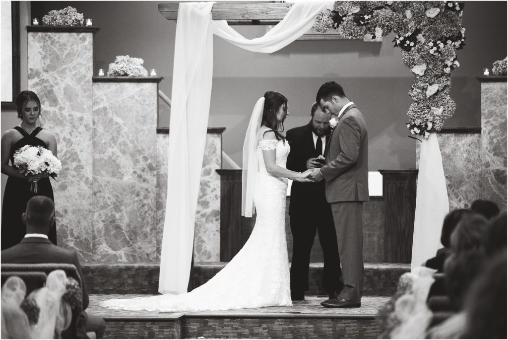 black and white image of bride and groom praying at the alter