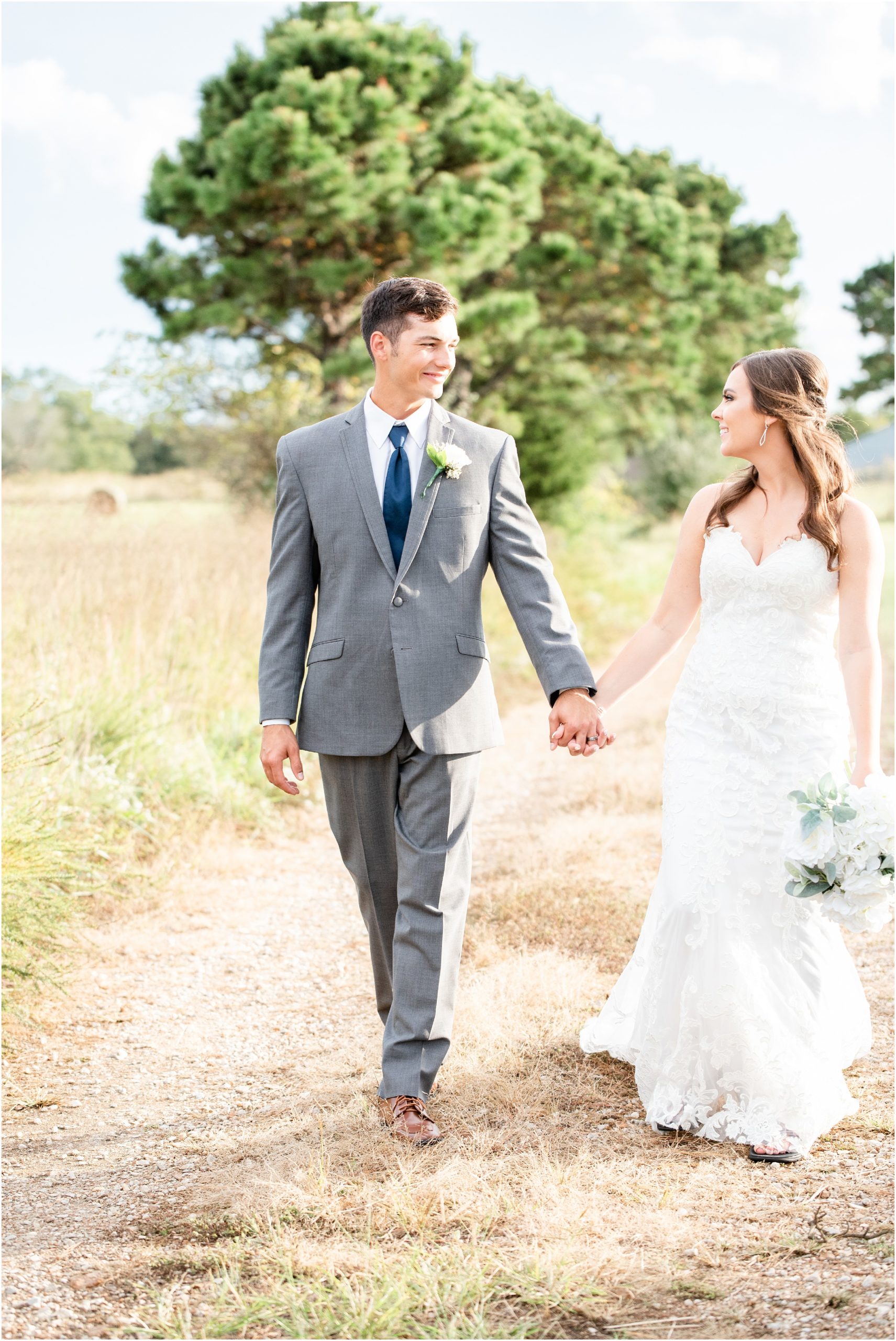 bride and groom walking down path in sun for portraits for linn, mo wedding
