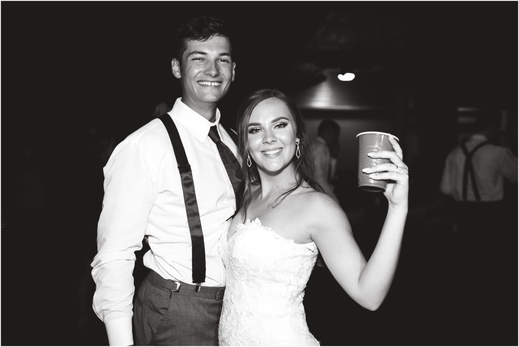 black and white photo of bride and groom smiling at camera during wedding reception in linn, mo