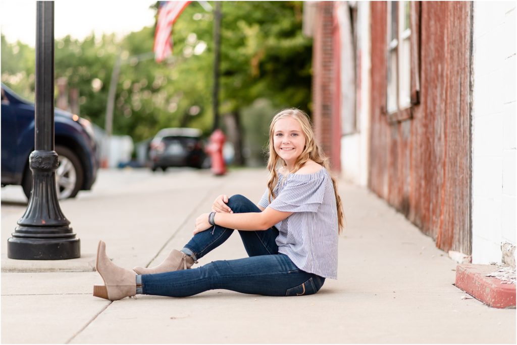 girl sitting on sidewalk for senior session in downtown Russellville, mo