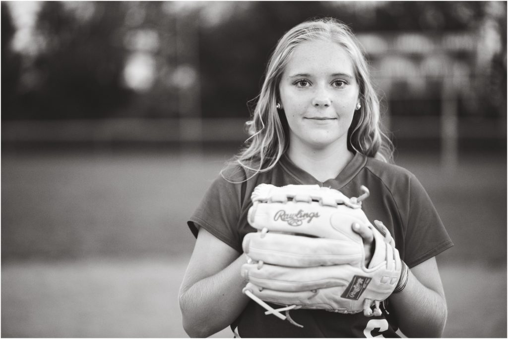 black and white image of senior girl in softball uniform and glove for senior session