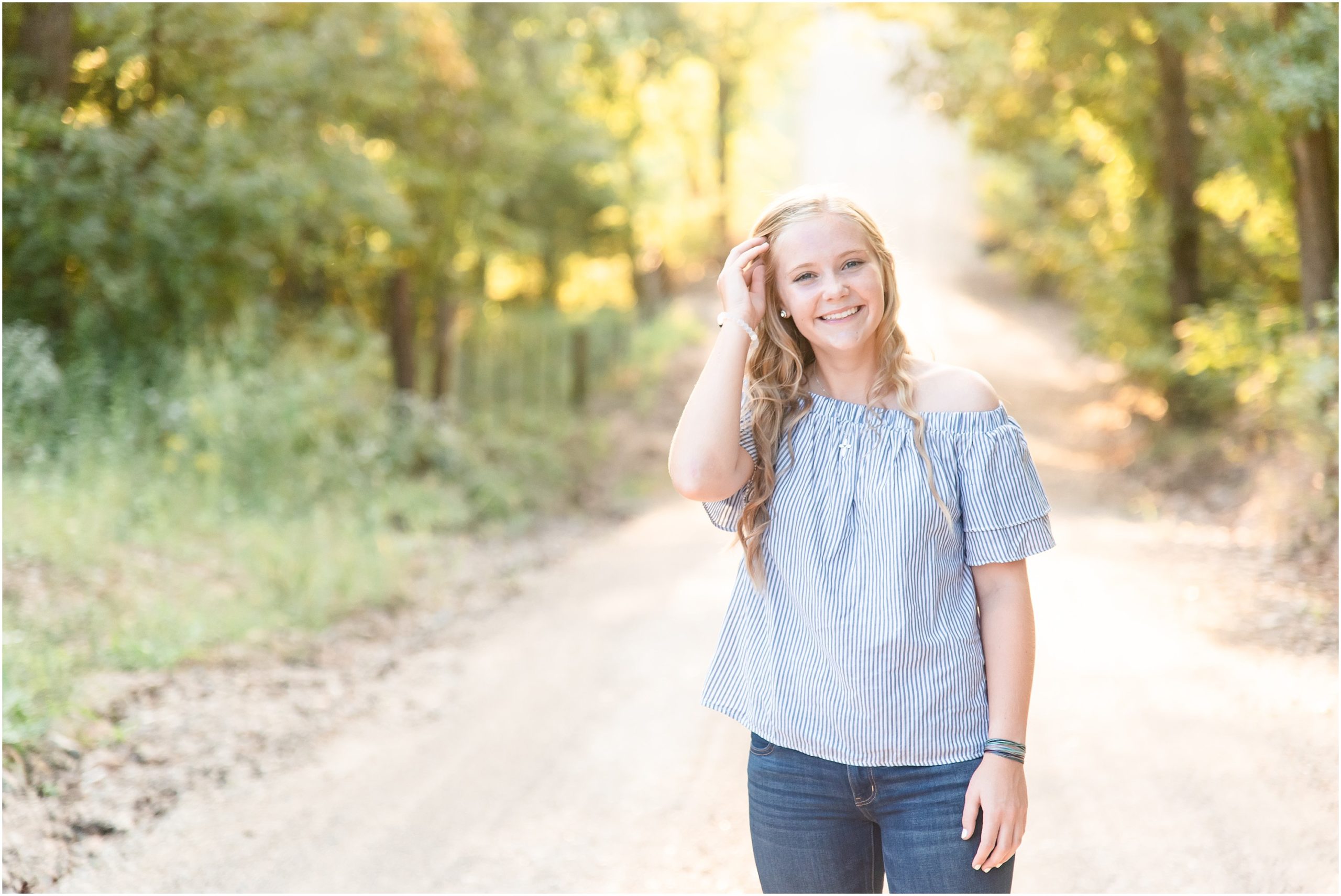 senior girl posing on gravel road in sunlight and blue shirt for Russellville high school senior session