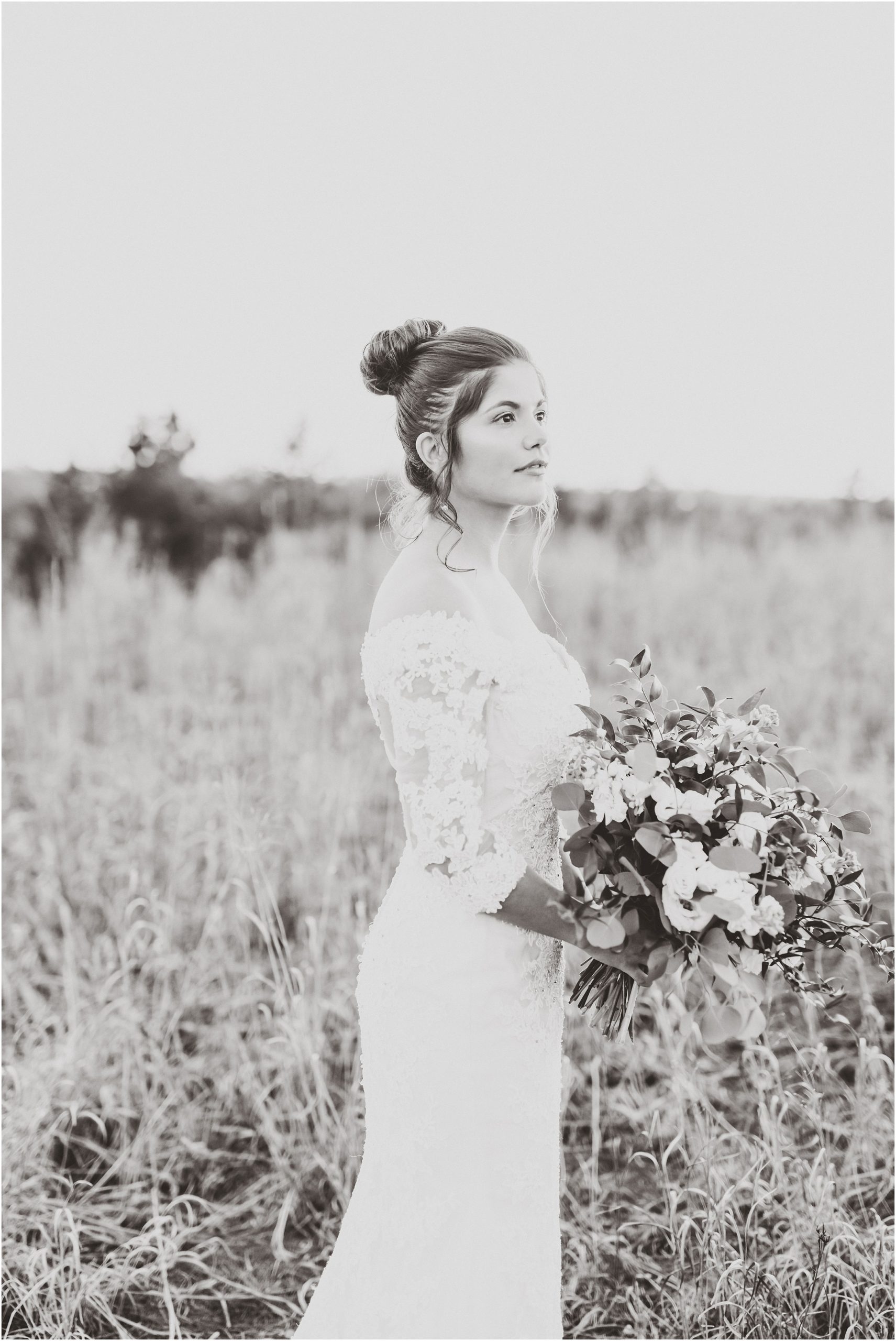 black and white image of bride looking into the distance in field at sunset for bridal session