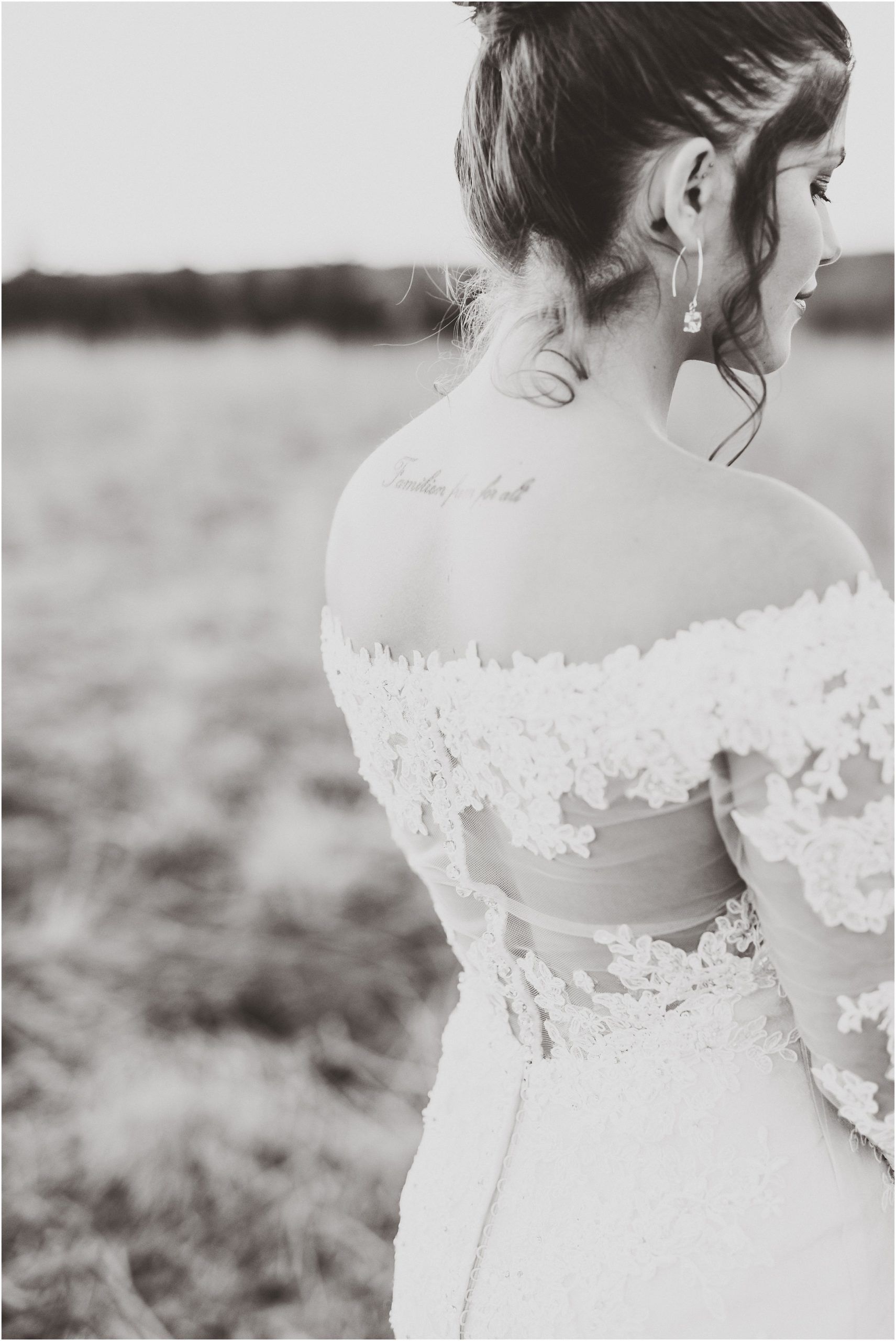 black and white image of bride's back tattoo and wedding dress during bridal session