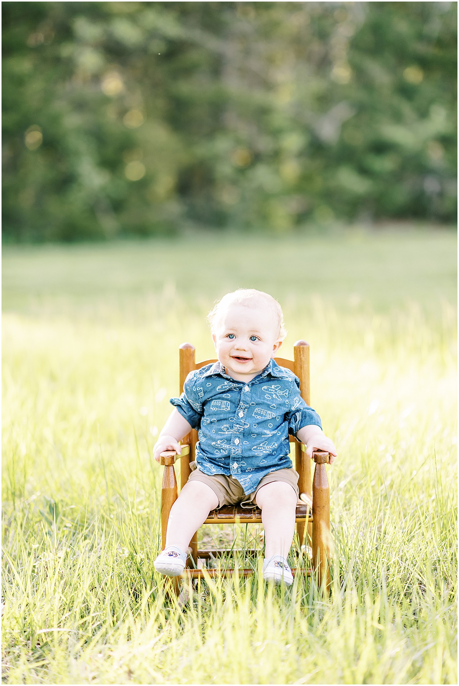 one year old boy in blue shirt sitting on wooden rocking chair in the grass